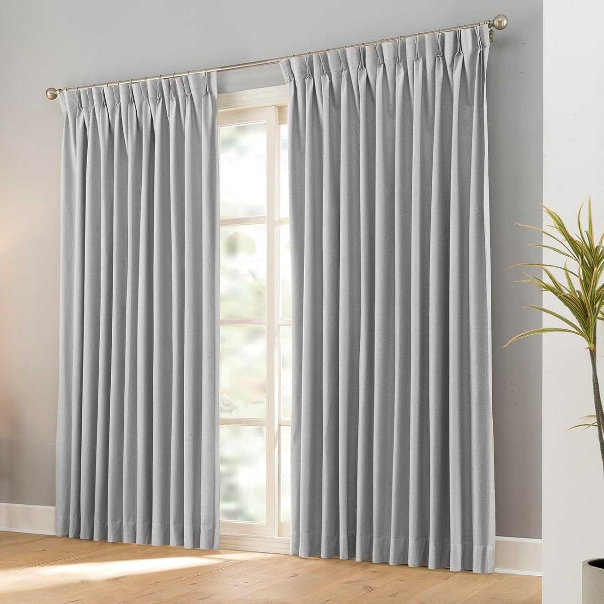 Pair of black faux linen blackout curtains with pencil pinch pleats hanging on a curtain rod
