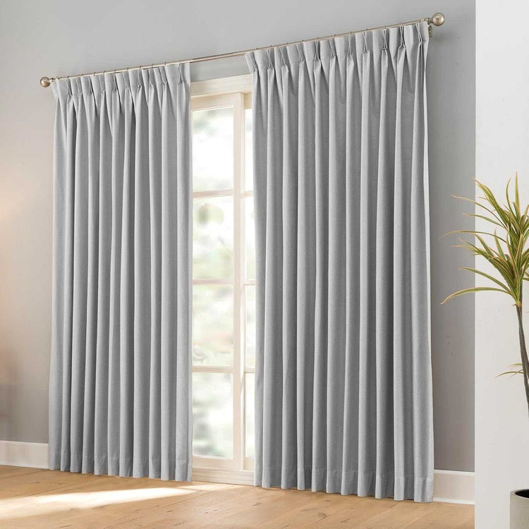 Pair of black faux linen blackout curtains with pencil pinch pleats hanging on a curtain rod